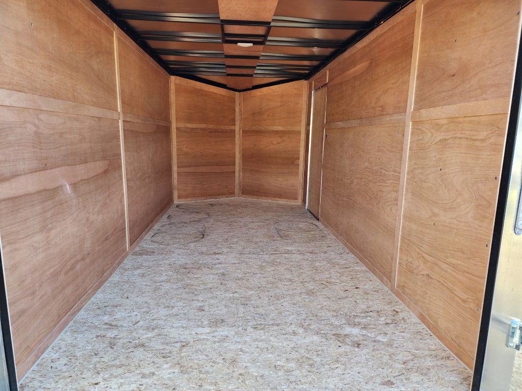 L'intérieur d'une remorque vide avec des murs en bois et un sol en béton.