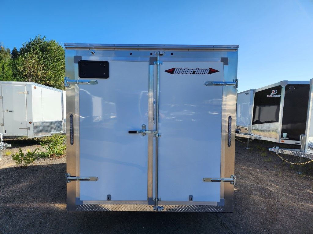 Une remorque blanche est garée sur un parking avec d'autres remorques.