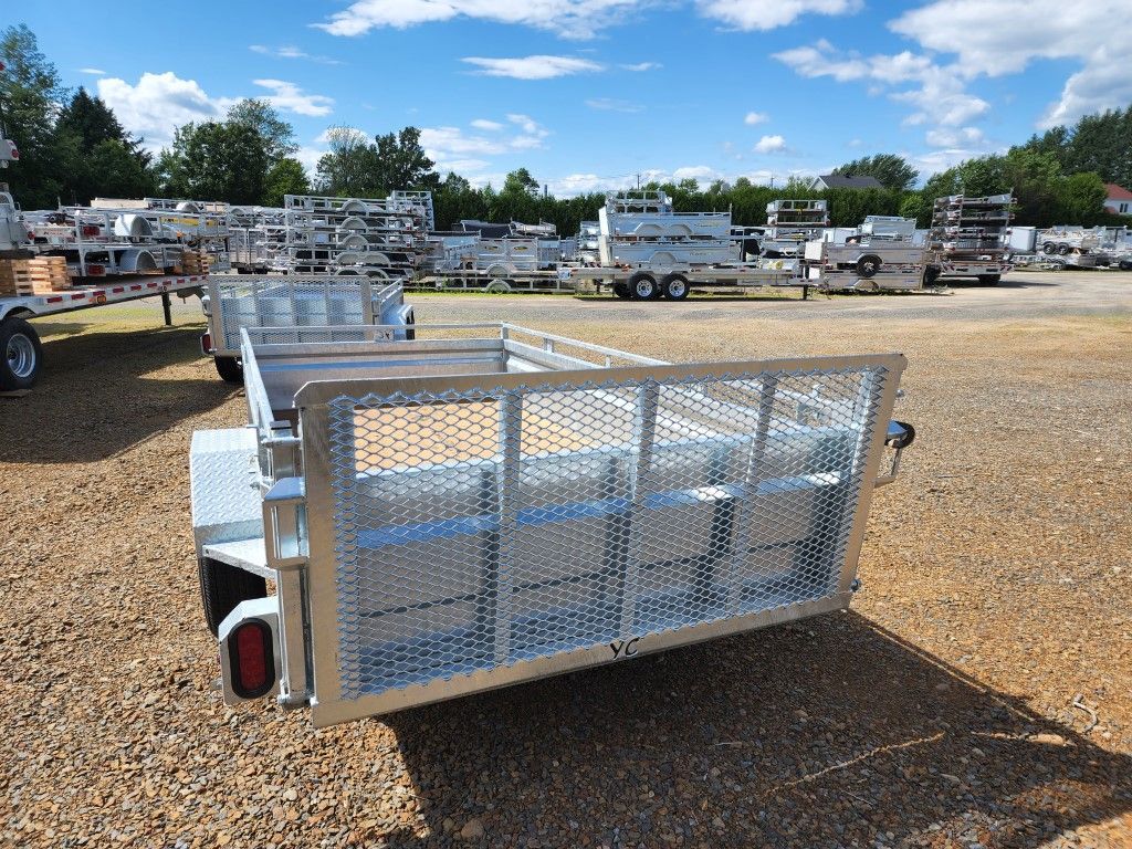 Une remorque est garée sur un terrain en gravier à côté d'un panneau.