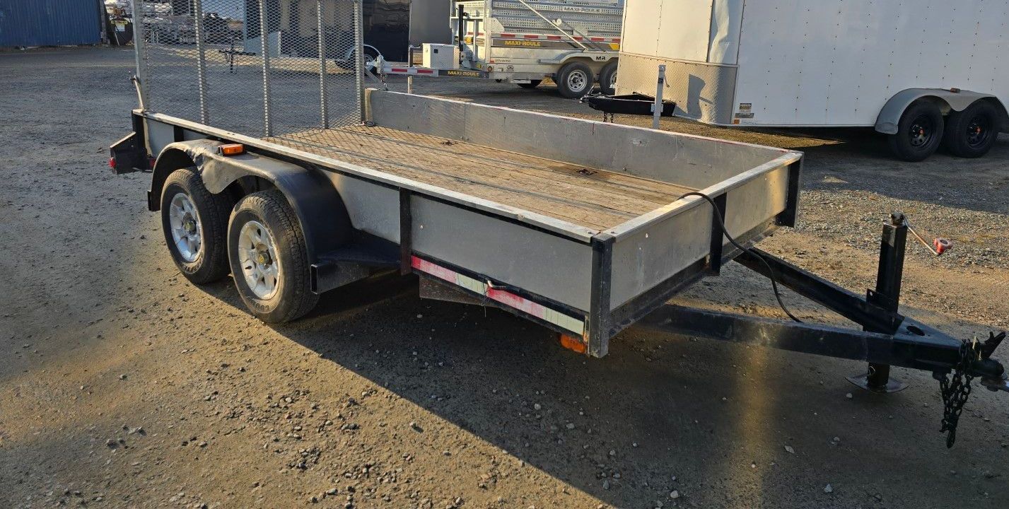 Une petite remorque est garée sur un terrain en gravier.