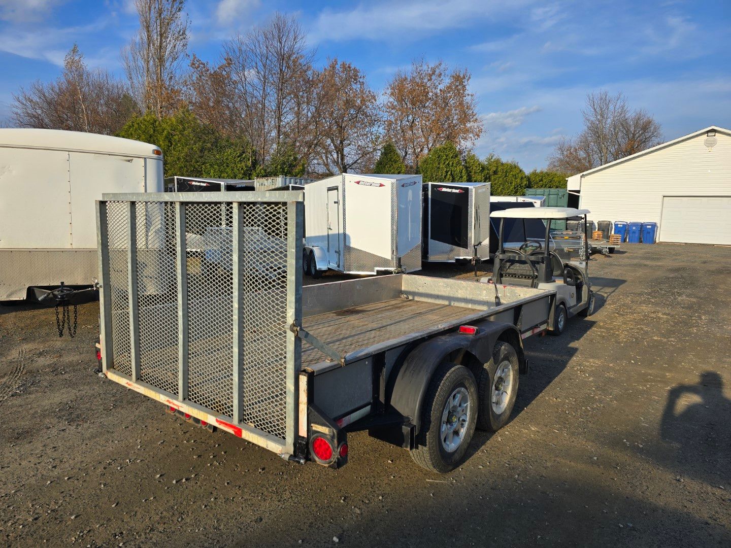 Une remorque avec une cage à l'arrière est garée dans un parking.