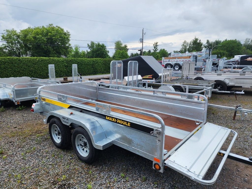 Une remorque de moto est garée sur un terrain en gravier.