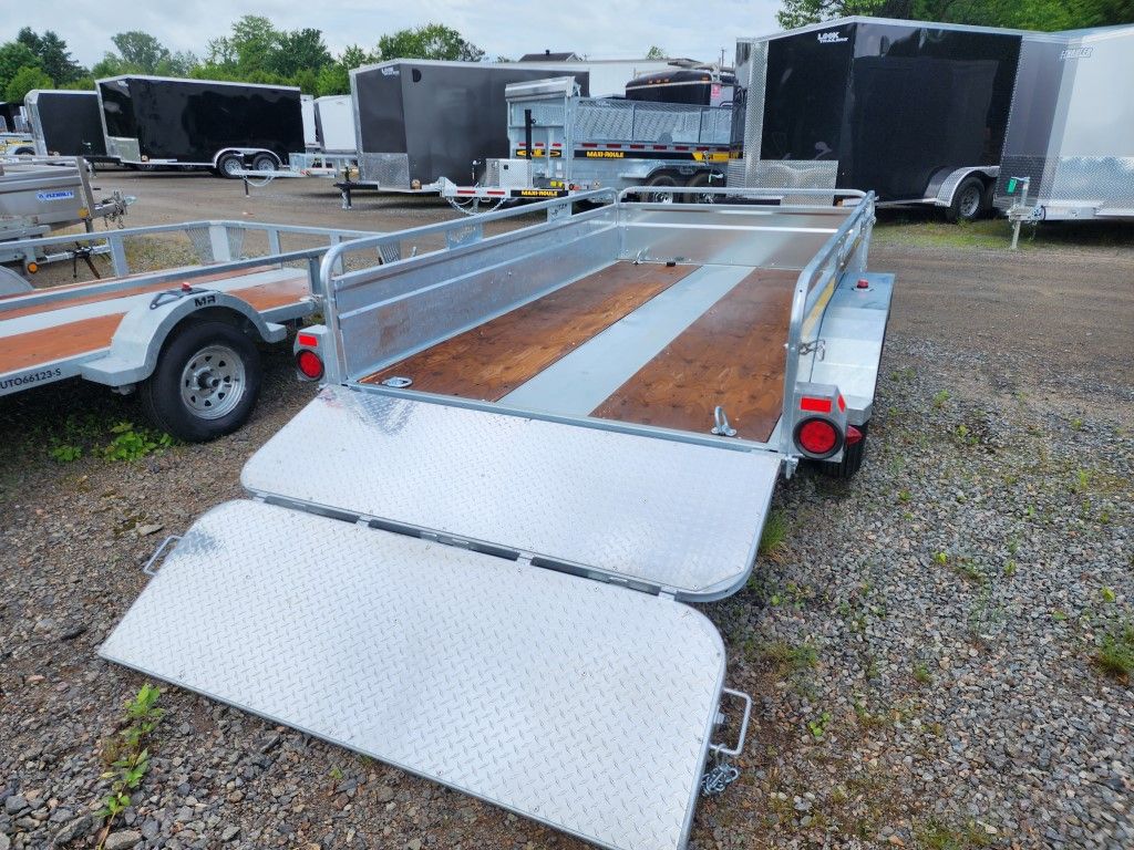 Une remorque de moto est garée sur un terrain en gravier.