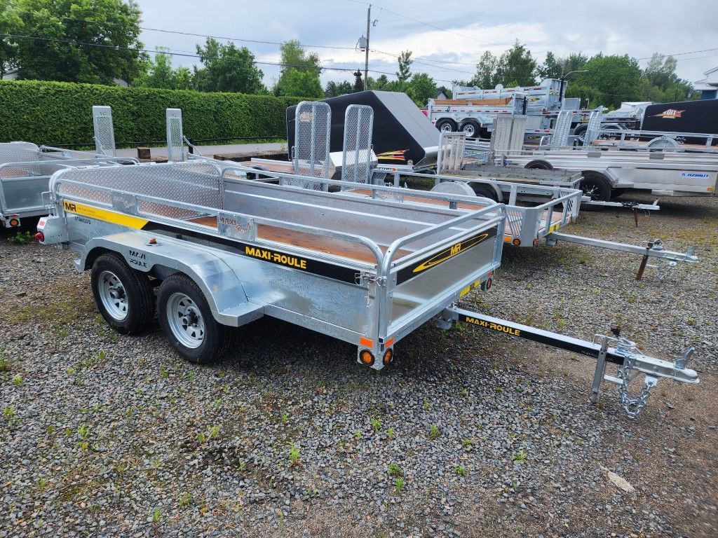 Une remorque avec une moto dessus est garée sur un terrain en gravier.