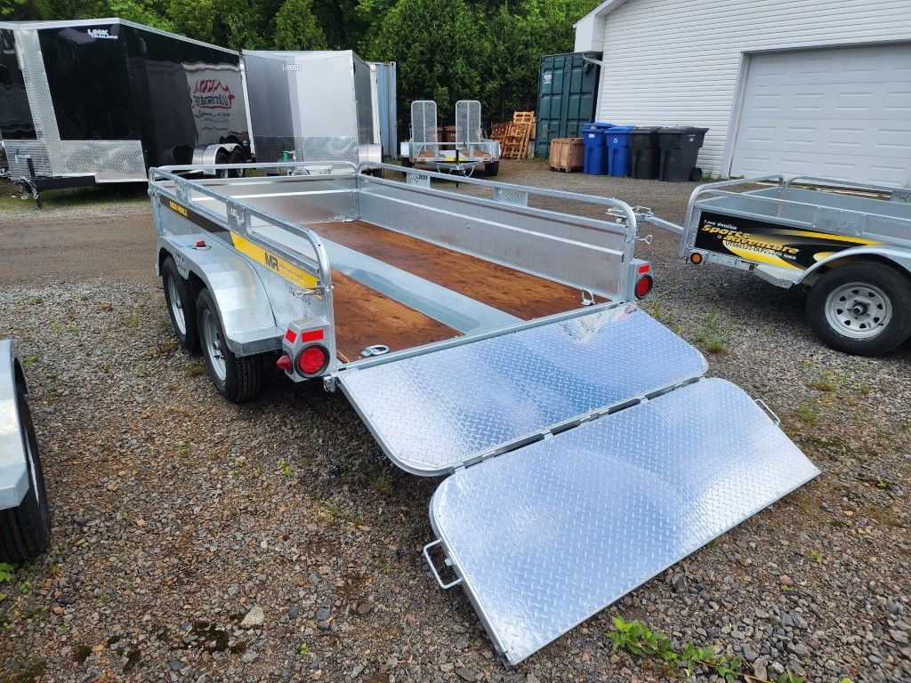 Une remorque est garée sur un terrain en gravier à côté d'un garage.