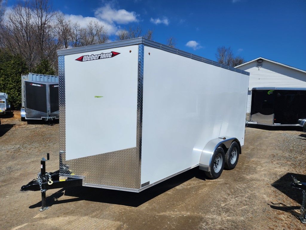 Une remorque blanche est garée devant un garage.