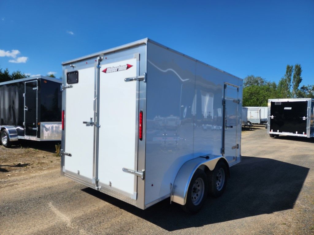 Une remorque blanche est garée sur un parking à côté d'une remorque noire.