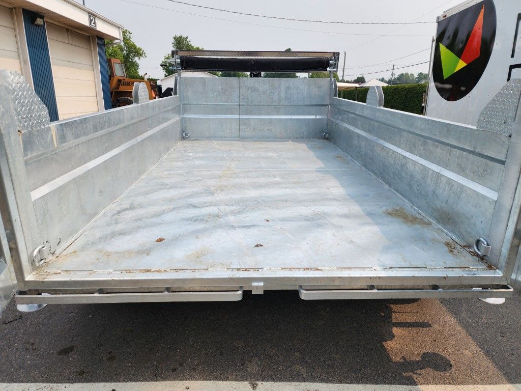 L'arrière d'une benne à ordures est vide et se trouve sur le bord de la route.