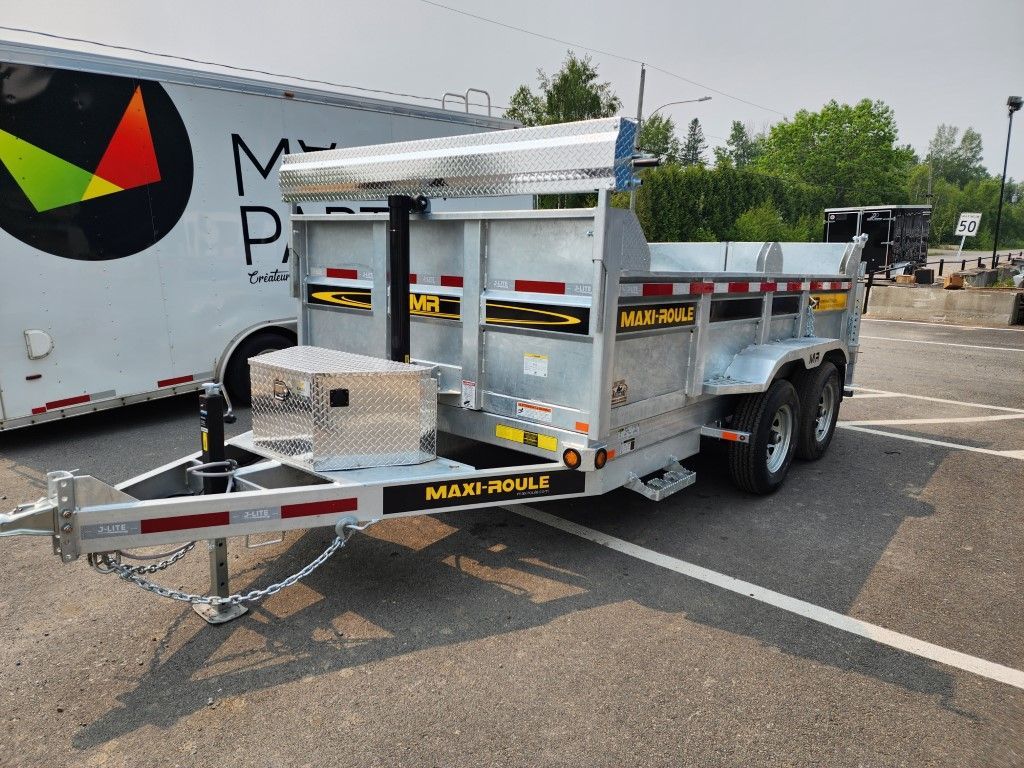Une remorque à benne basculante est garée sur un parking à côté d'une remorque blanche.