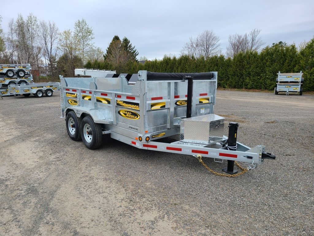 Une remorque à benne basculante est garée sur un terrain en gravier.