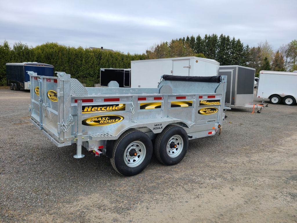 Une remorque à benne basculante est garée sur un terrain en gravier.