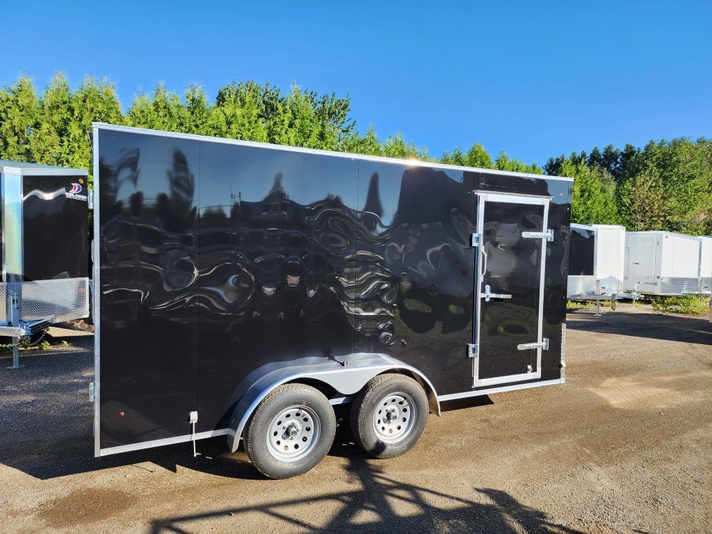 Une remorque noire est garée sur un parking.