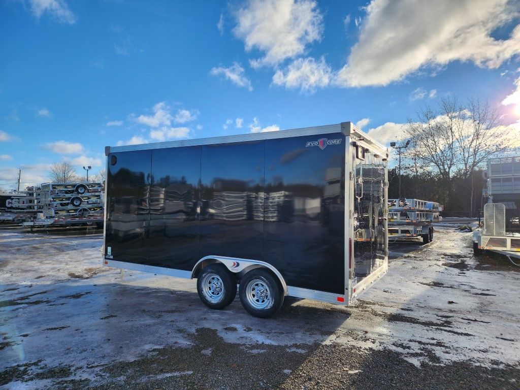 Une remorque noire est garée sur un parking enneigé.