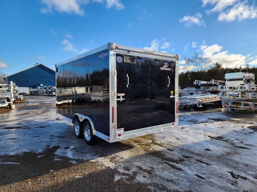 Une remorque noire est garée sur un parking enneigé.
