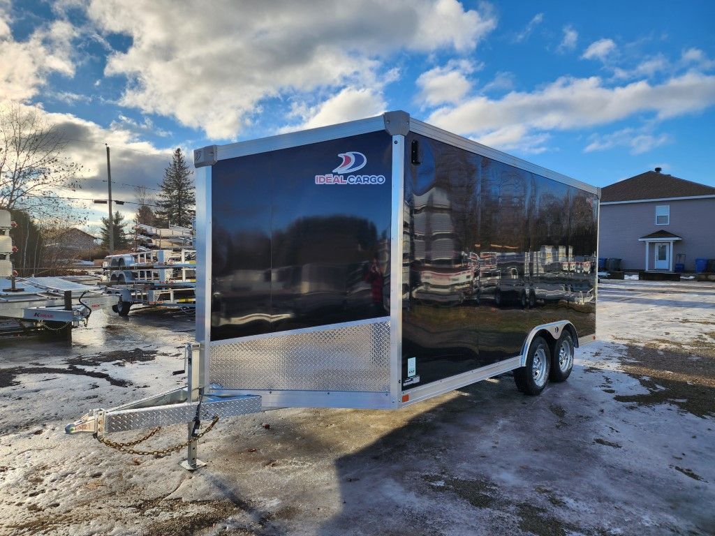 Une remorque noire et argentée est garée sur un parking enneigé.