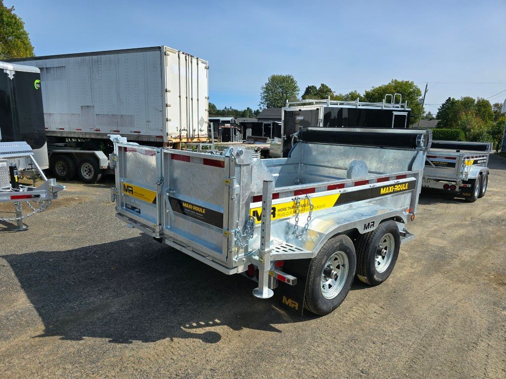 Une remorque à benne basculante est garée sur un parking à côté d'un camion.