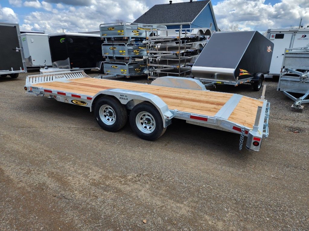 Une remorque avec un pont en bois est garée dans un parking.