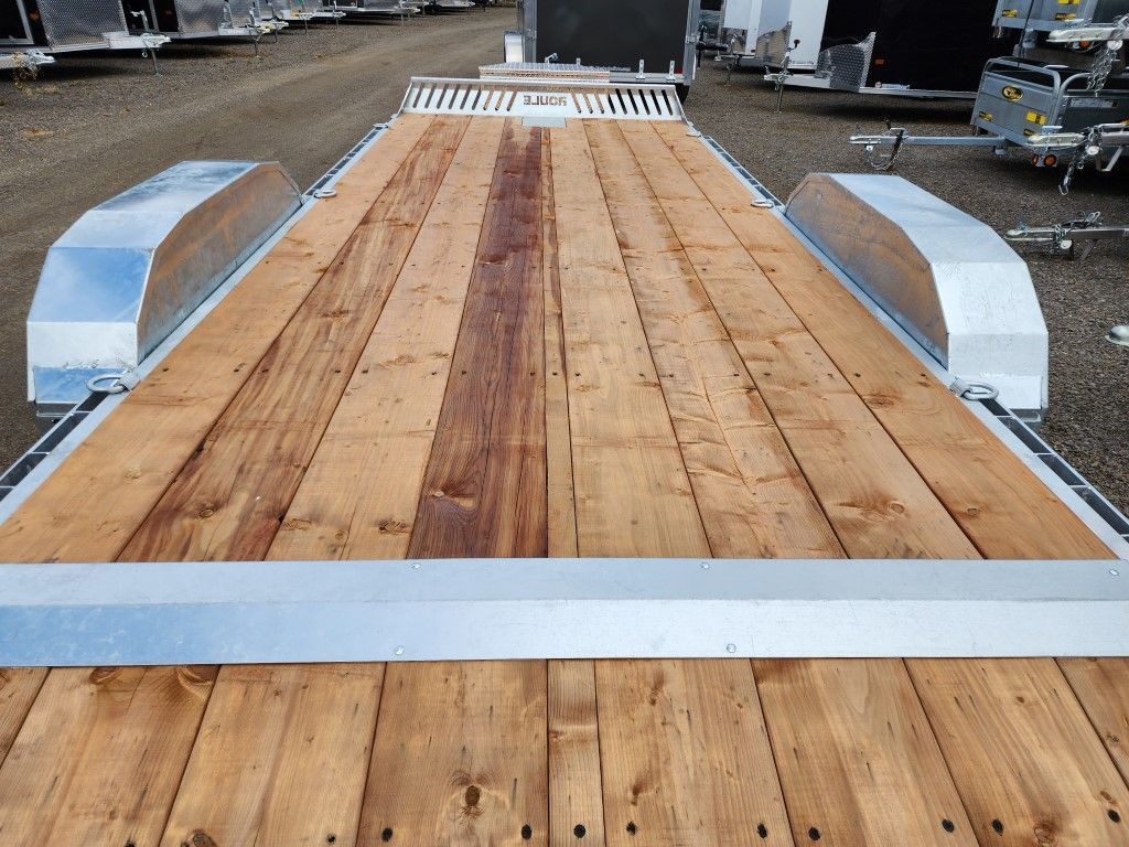 L'arrière d'une remorque avec un pont en bois et des ailes en aluminium.