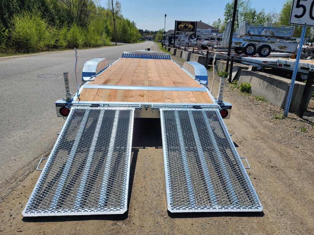 Une remorque avec un pont en bois est garée sur le bord de la route.