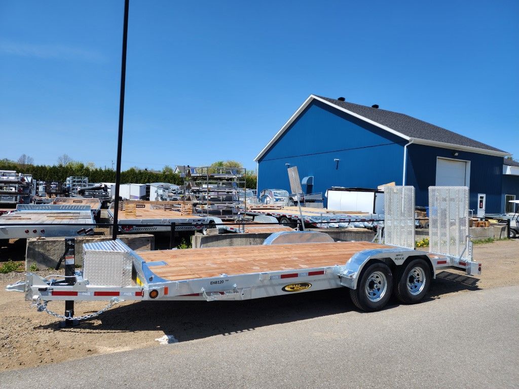 Une remorque est garée devant un bâtiment bleu.