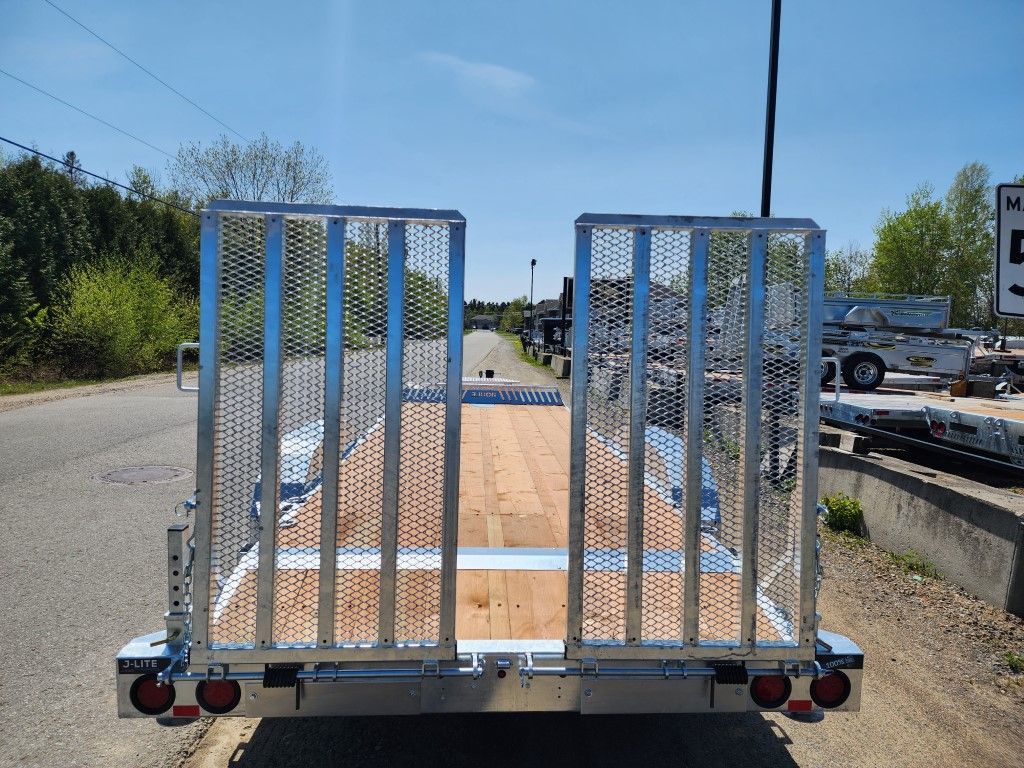 Une remorque avec un pont en bois est garée sur le bord de la route.