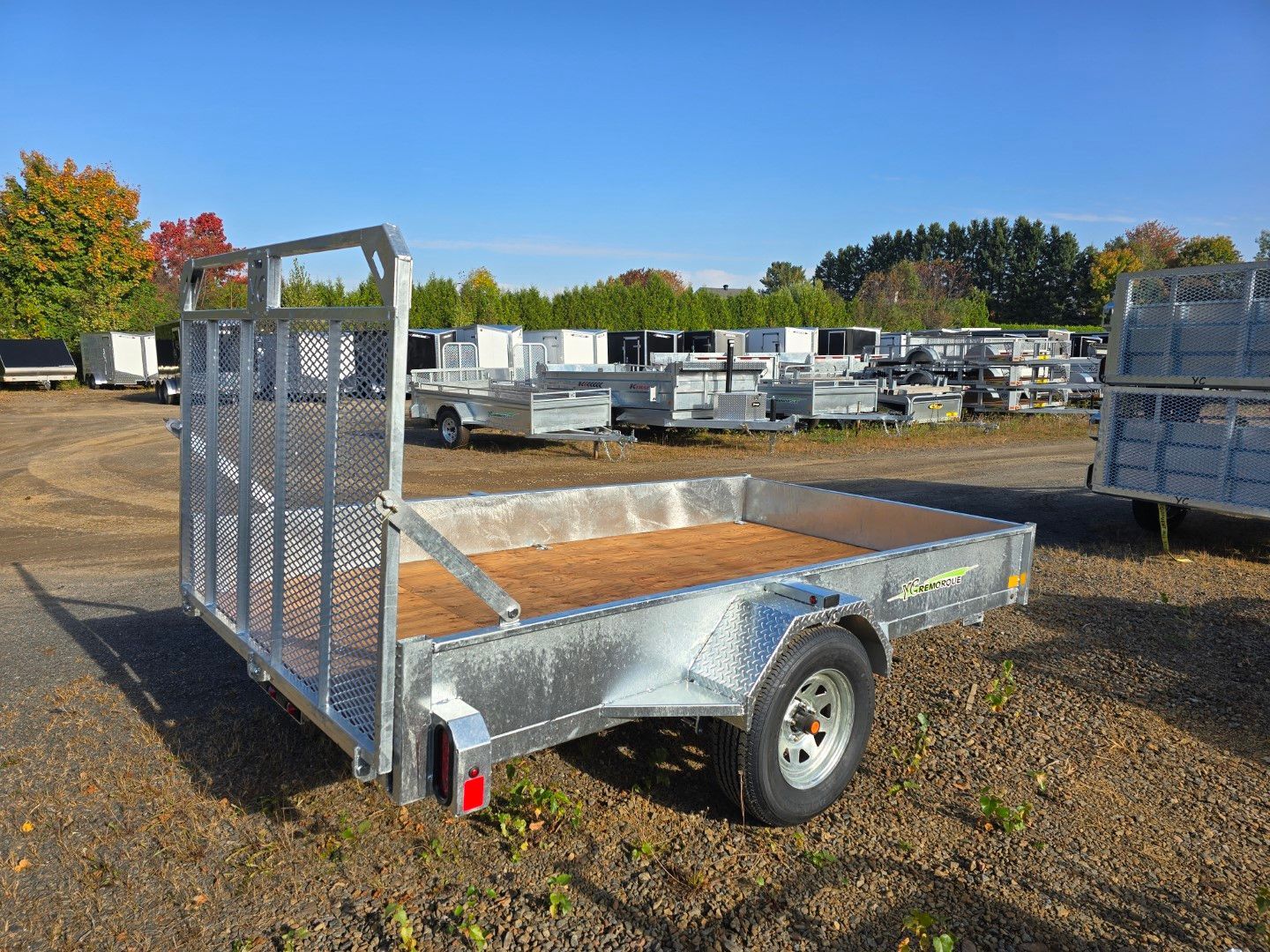 Une remorque avec une terrasse en bois est garée sur un terrain.
