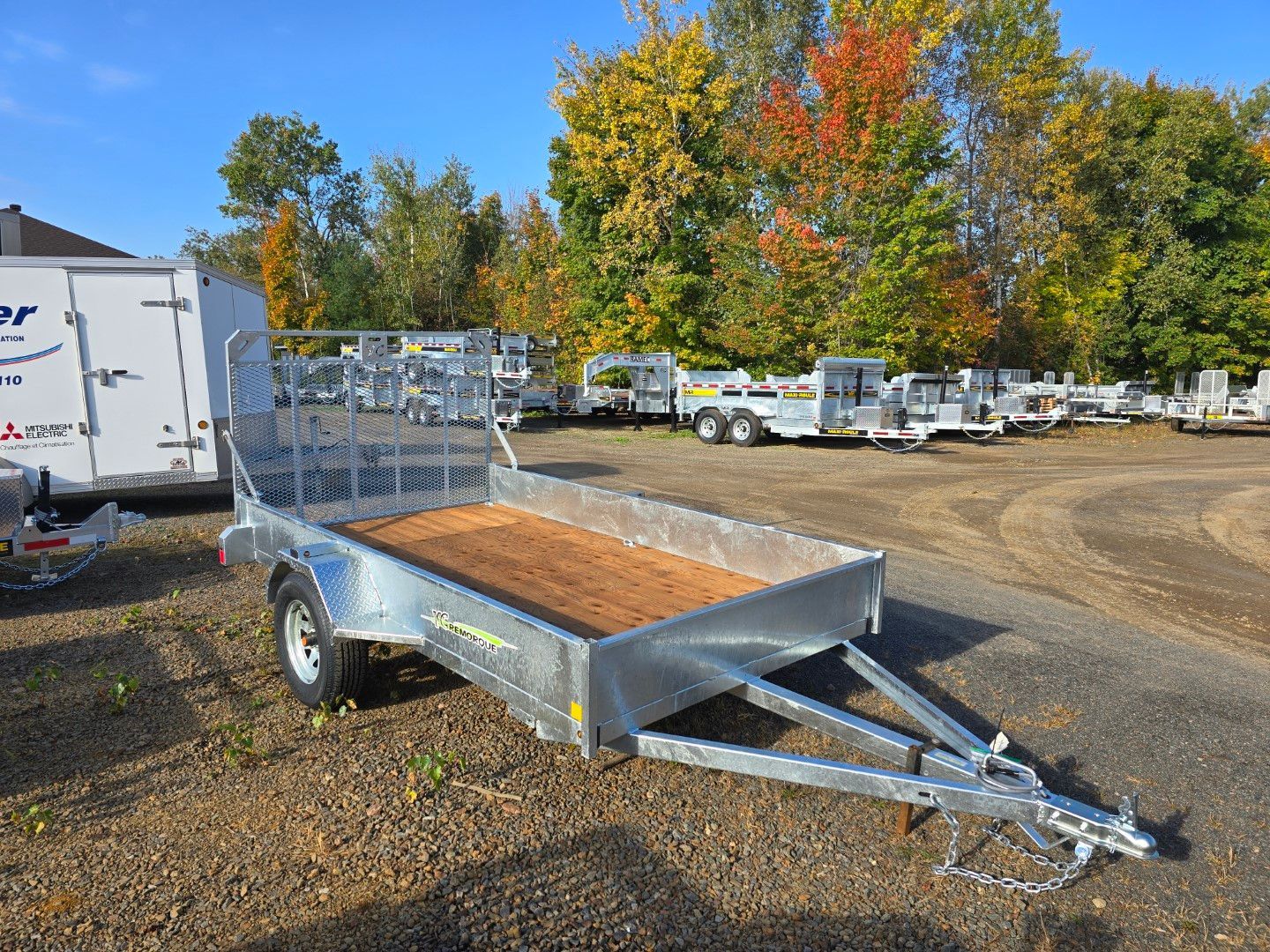 Une remorque avec une terrasse en bois est garée sur un terrain.