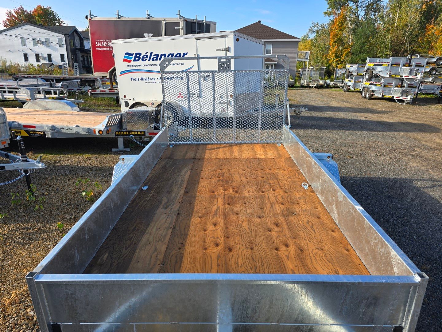 Une remorque avec un plancher en bois est garée sur un parking.