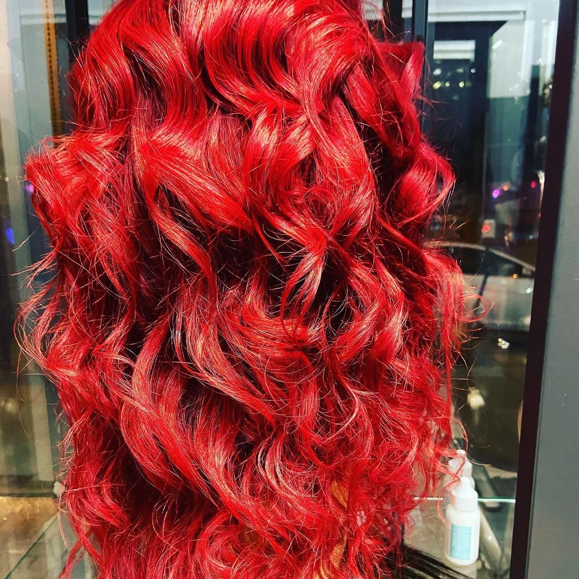 Woman with bright red curly hair and a black face mask.
