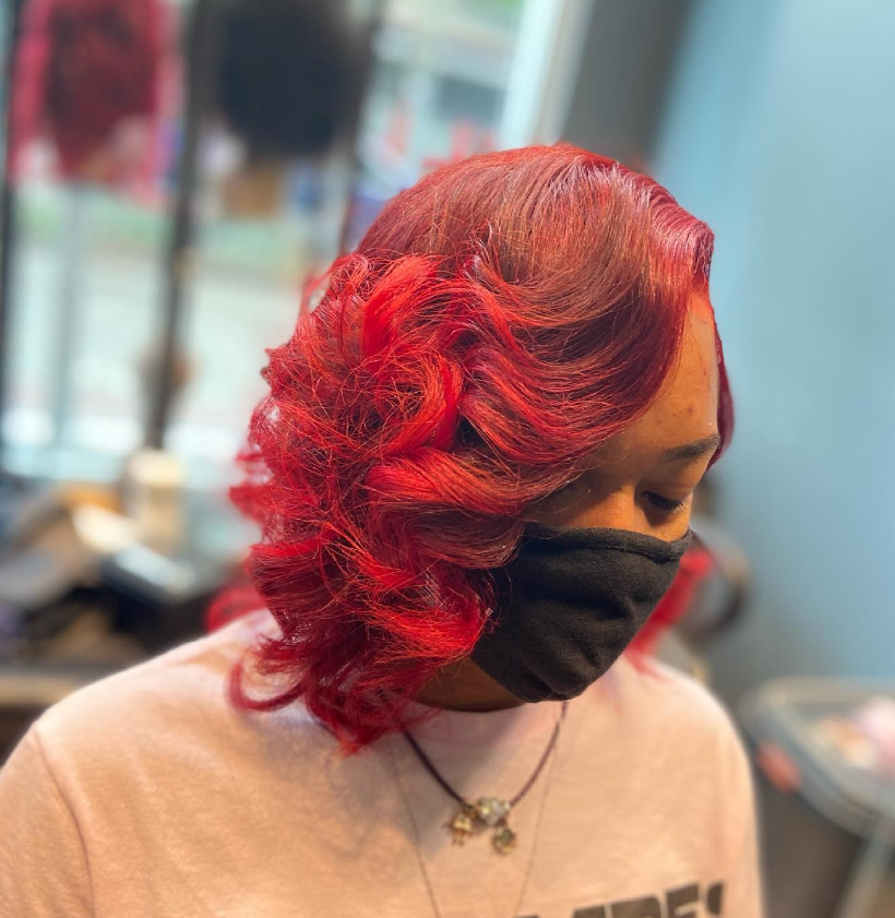 Woman with bright red curly hair and a black face mask.