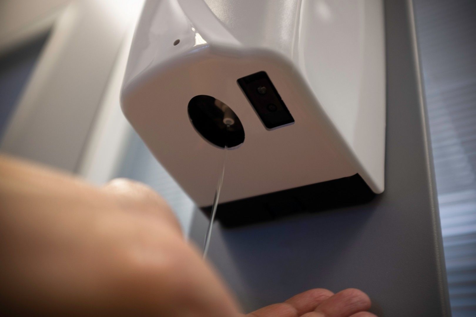 Una persona sta utilizzando un dispenser di disinfettante per le mani appeso a una parete.