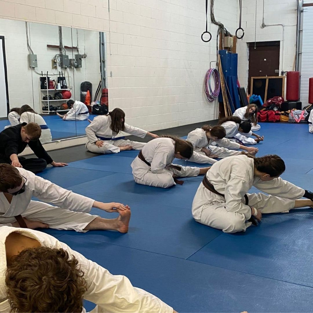 Two men grappling on a mat, one in blue, the other in black.