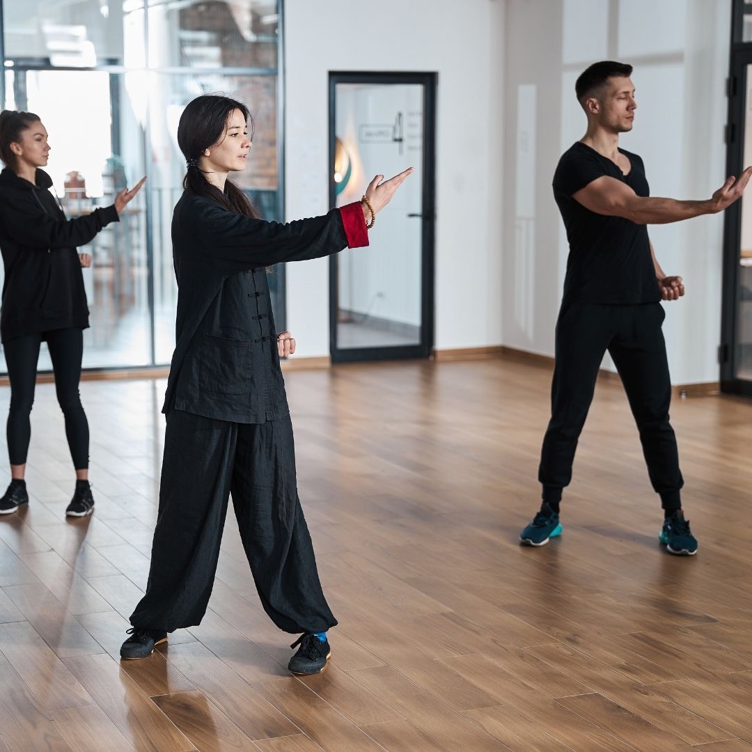 Group of children in martial arts attire posing, some with arms around each other, in a gym.