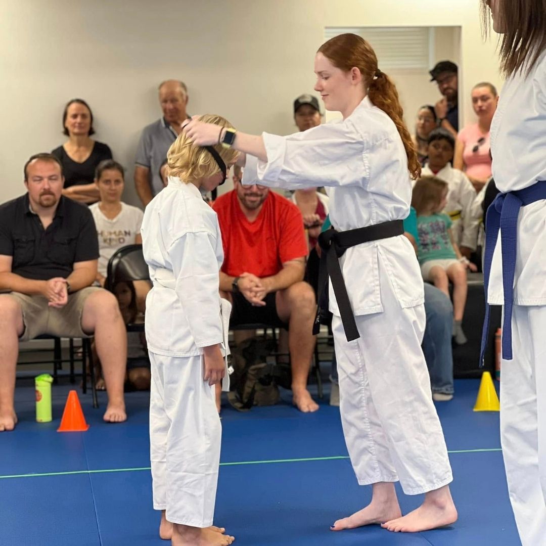 Two children grappling on a mat, one in a headlock.