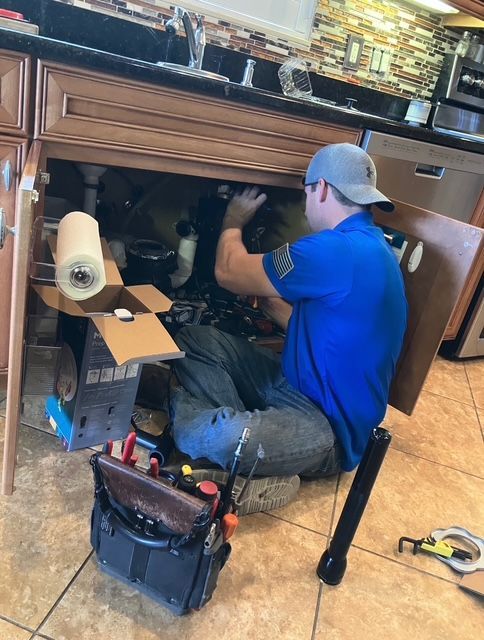 A man is fixing a dishwasher in a kitchen.