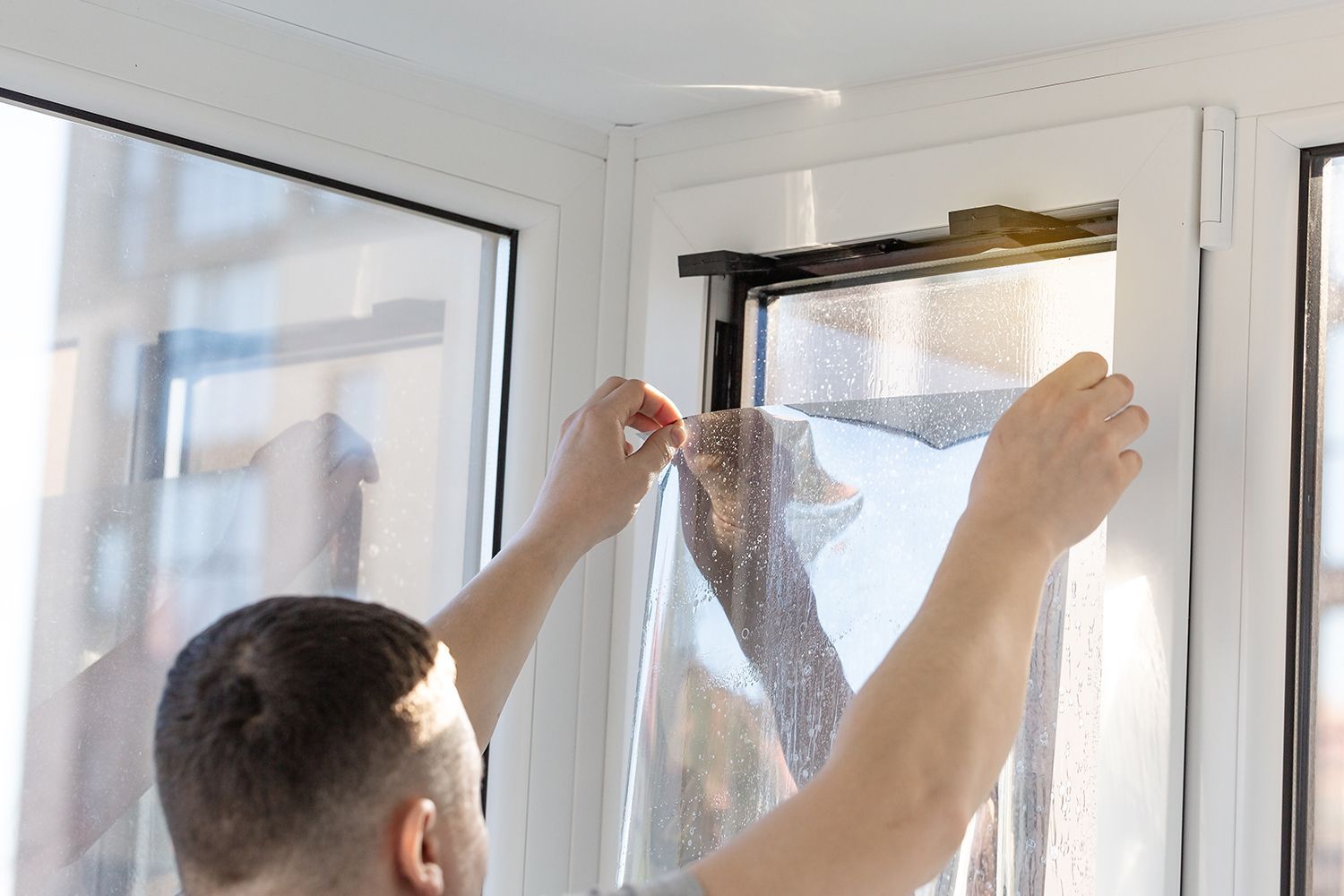 A technician installs a tinted film on an office window. A technician installs a tinted film on an office window.