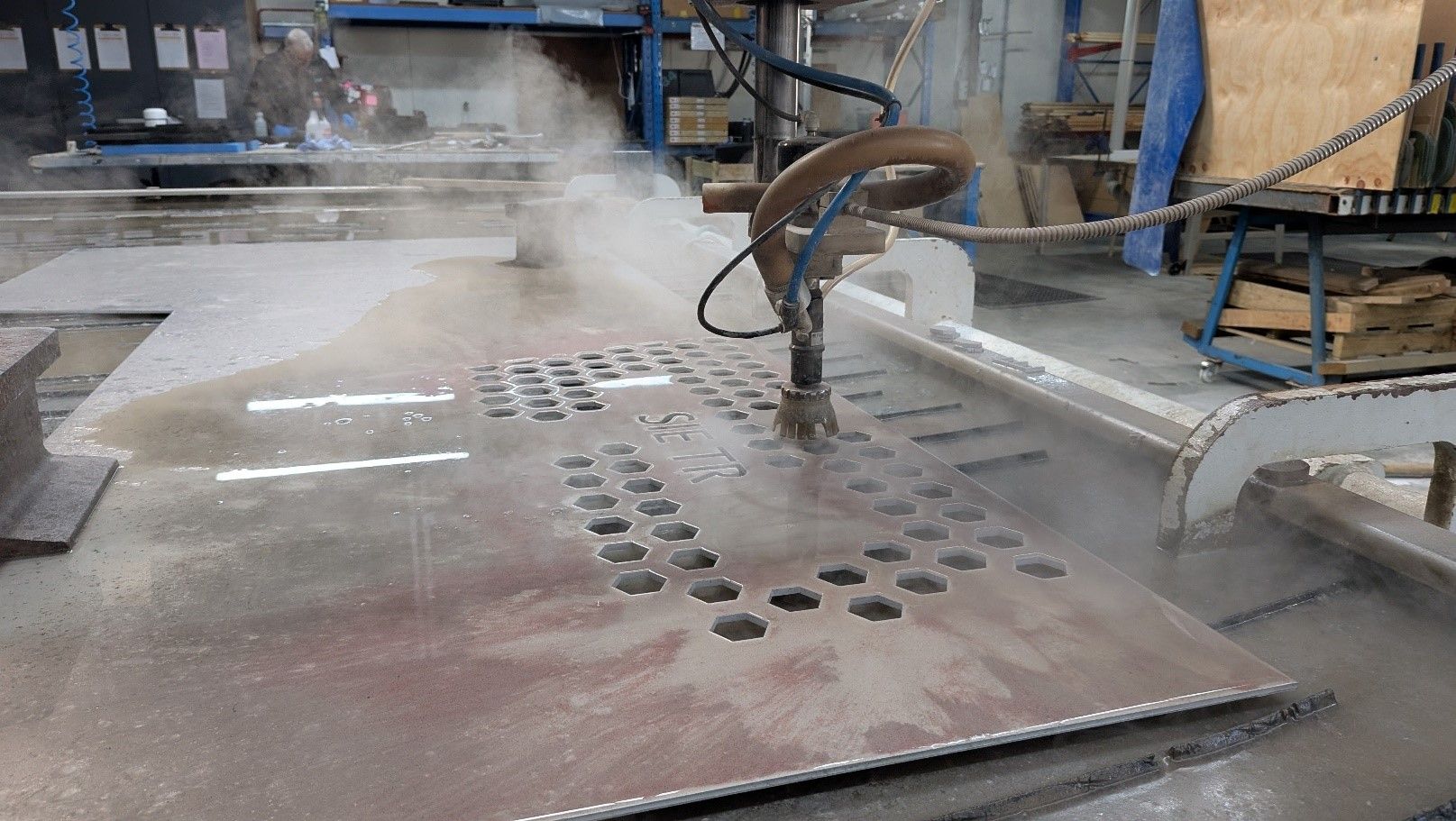 CNS Industrial waterjet cutting machine precisely cutting hexagonal patterns and text into a metal s