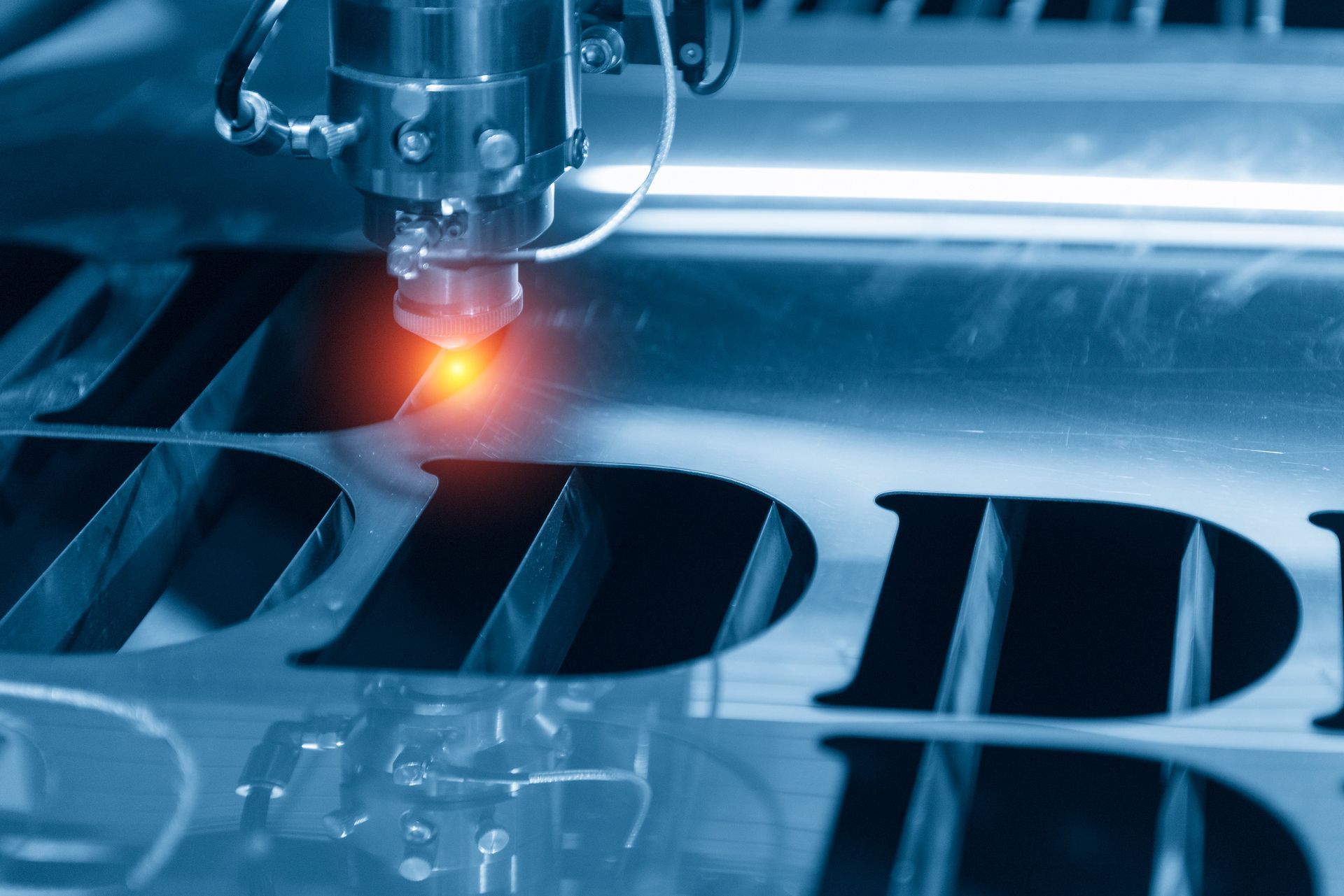 Closeup to a CNC cutting in process with a laser and some water sprinkled on the metal sheet.
