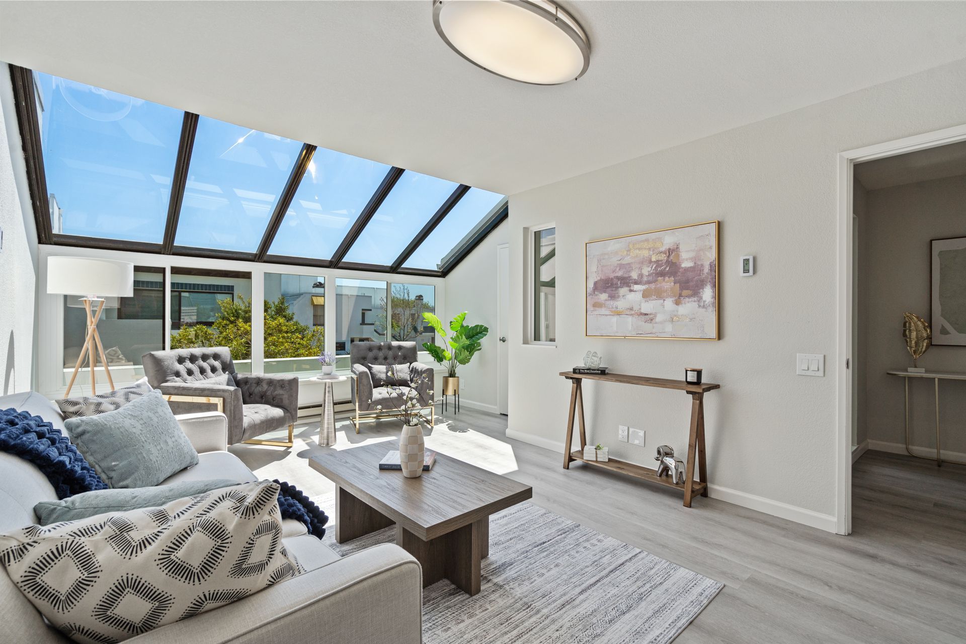 A living room with a couch , table , chairs and a skylight.