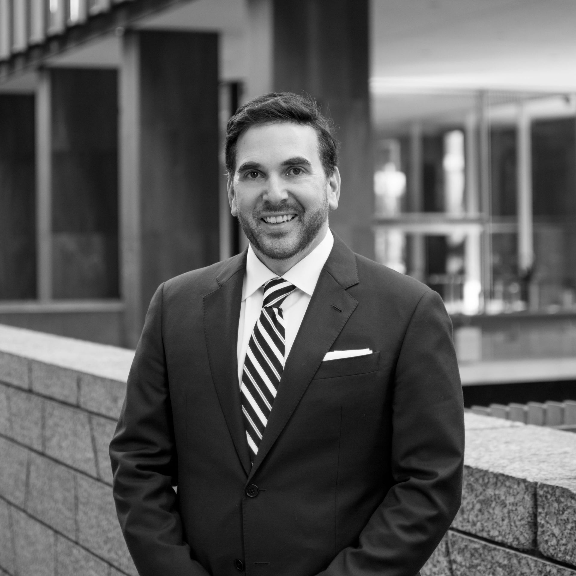 A man in a suit and tie is standing in front of a building.