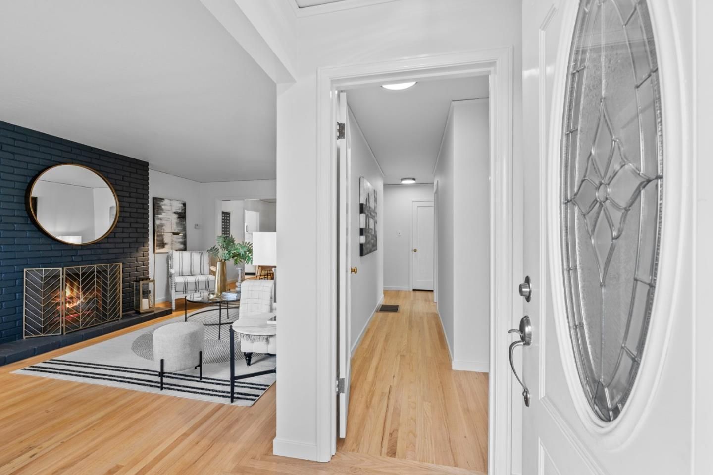 A hallway leading to a living room with a fireplace and a mirror.