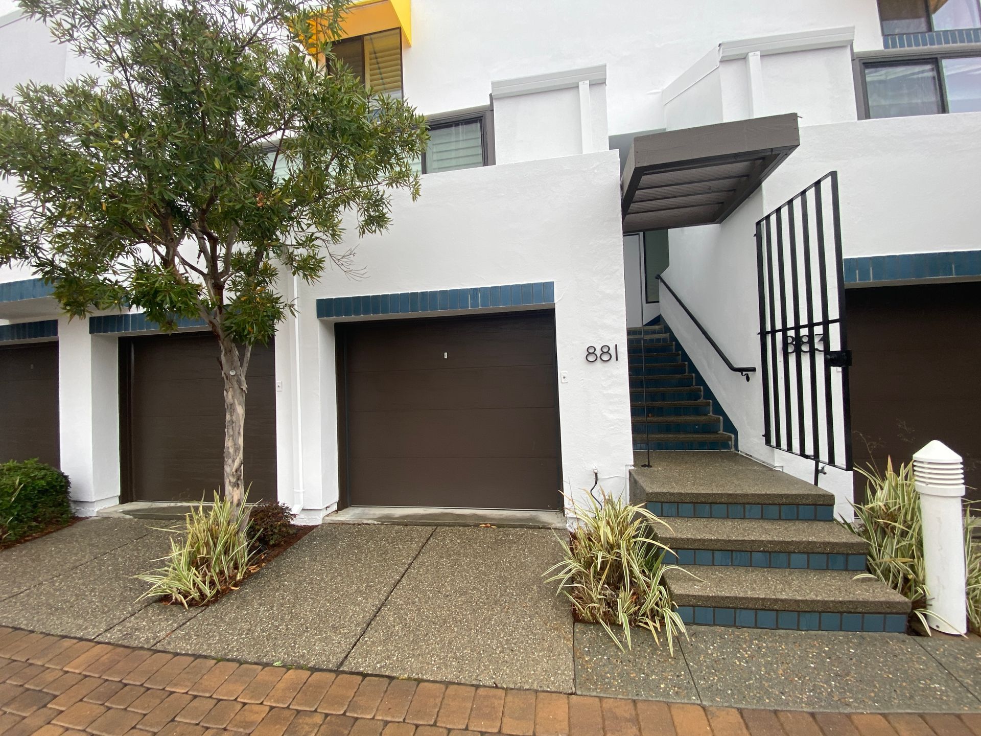 A white building with brown garage doors and stairs