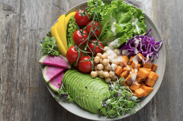 A bowl of vegetables and chickpeas on a wooden table.