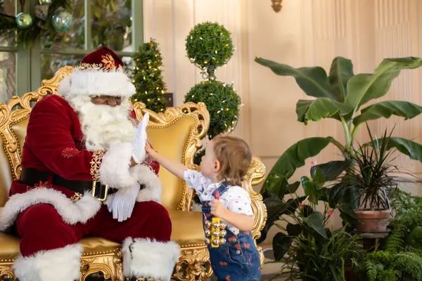 A little girl is reaching for a letter from santa claus.