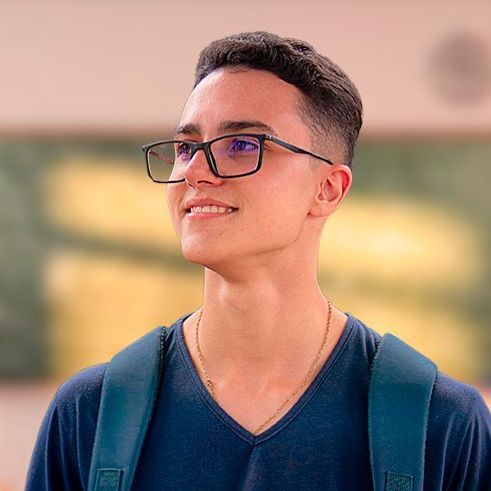 um jovem de óculos e mochila está sorrindo.