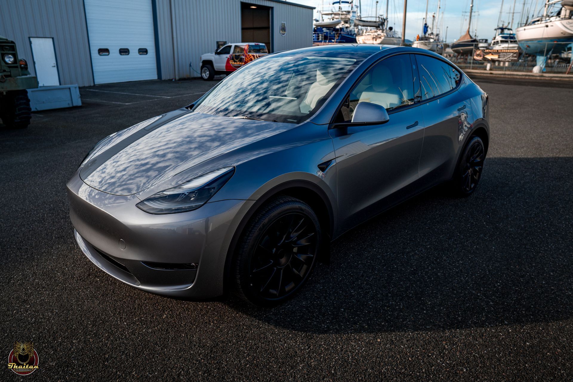 A gray tesla model y is parked in front of a garage.