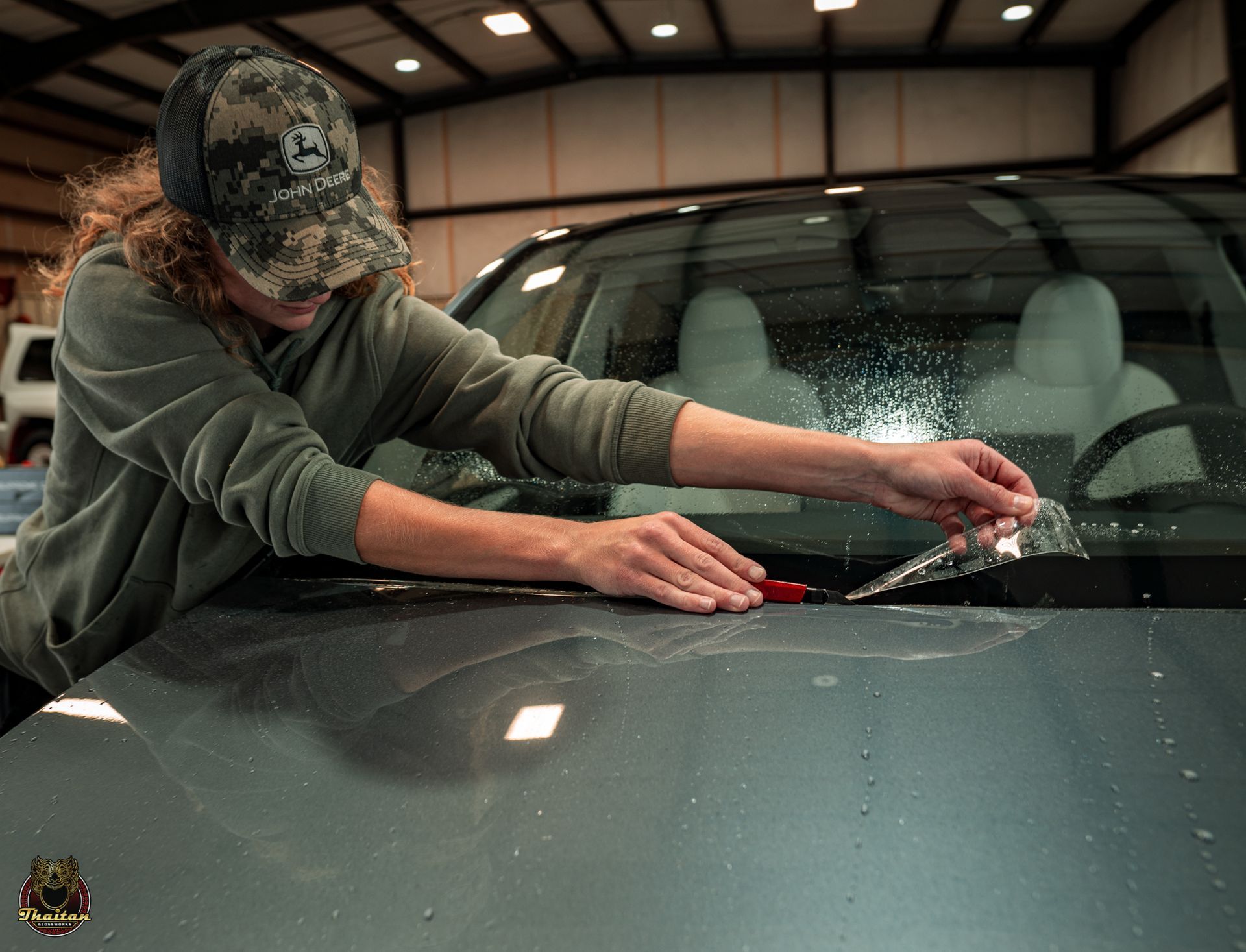 A man is applying a protective film to the hood of a car.