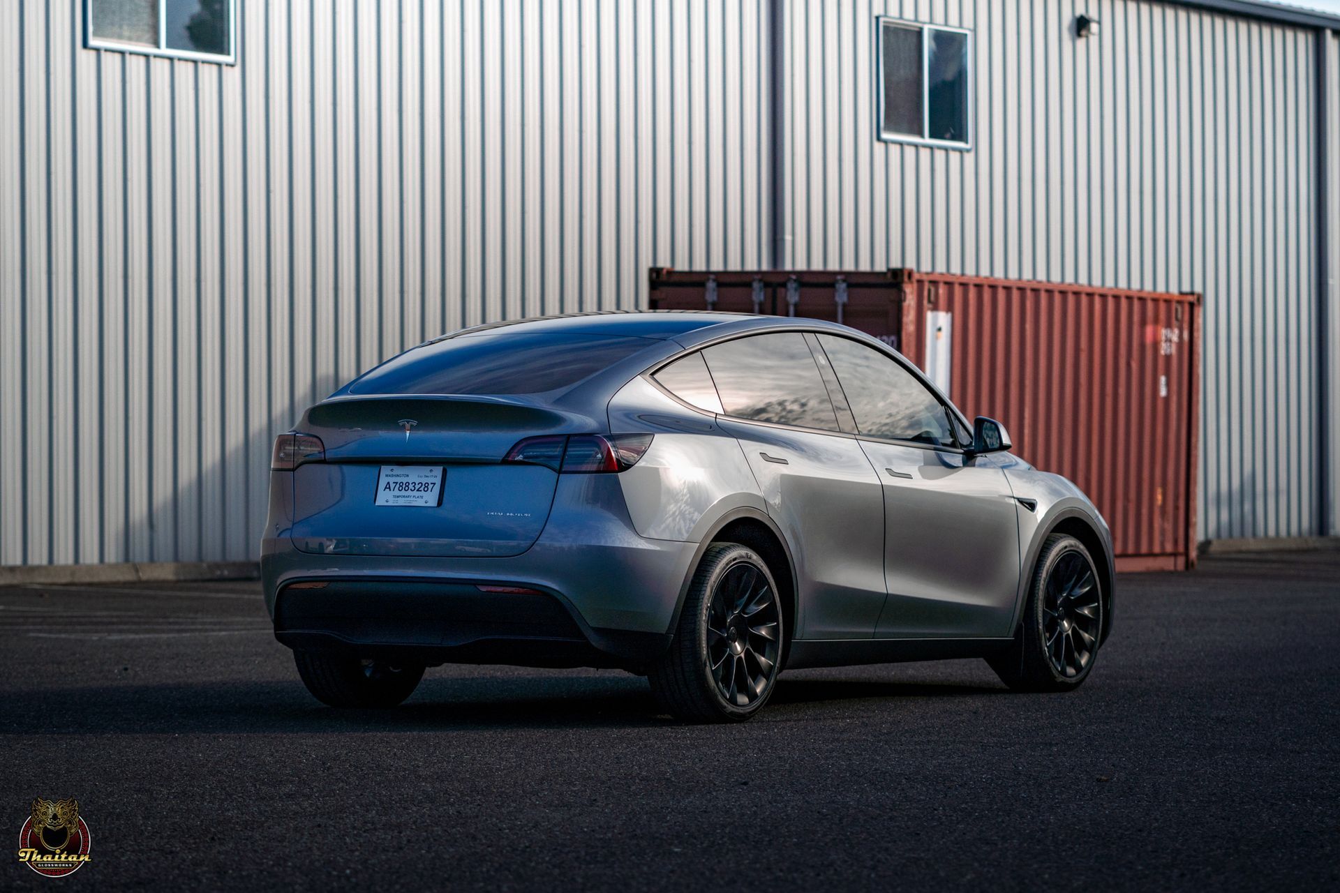 A tesla model y is parked in front of a building.
