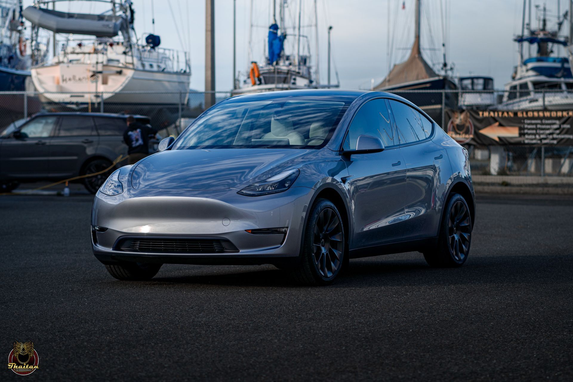 A tesla model y is parked in front of a marina.