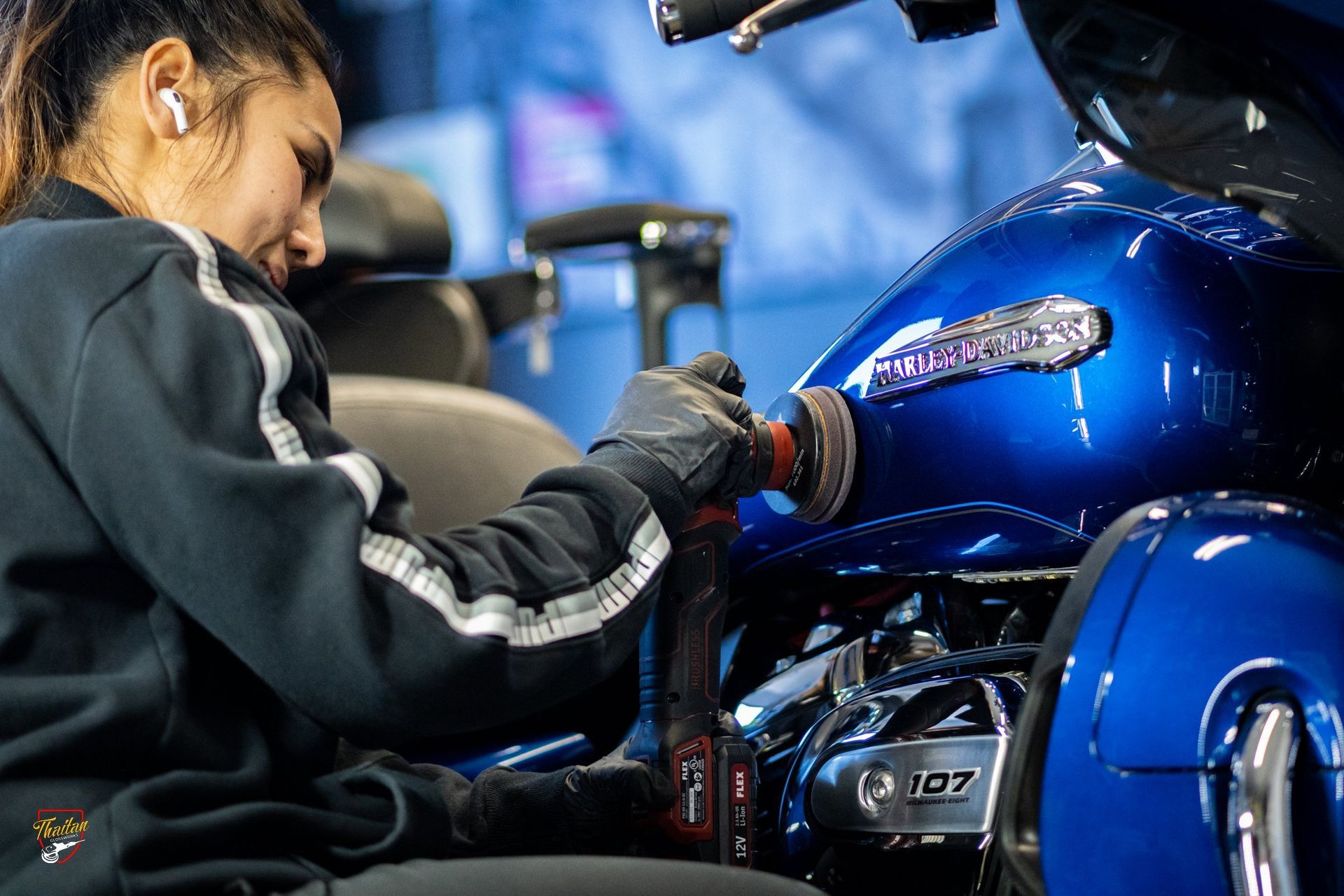 A woman is using a grinder on a wall.
